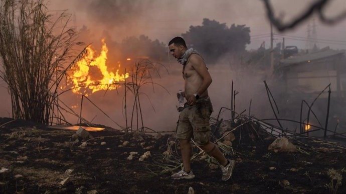 Un voluntario colabora en la extinción de las llamas de un incendio en Penteli, a las afueras de Atenas (foto: EP)