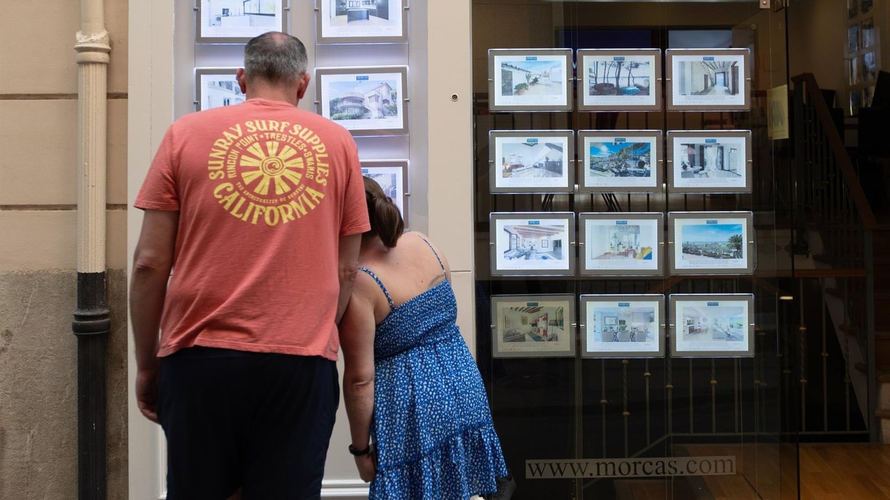 Dos personas observan los anuncios de viviendas en venta en una inmobiliaria (foto: EP)